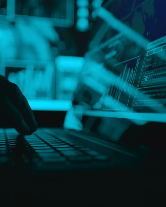 Hands typing code on a laptop lit in blue